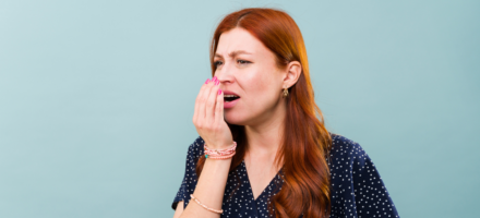 woman with a concerned look on her face while smelling her breath