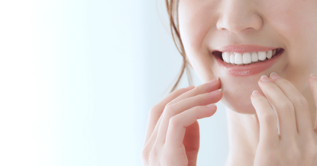 woman touching her gums while smiling