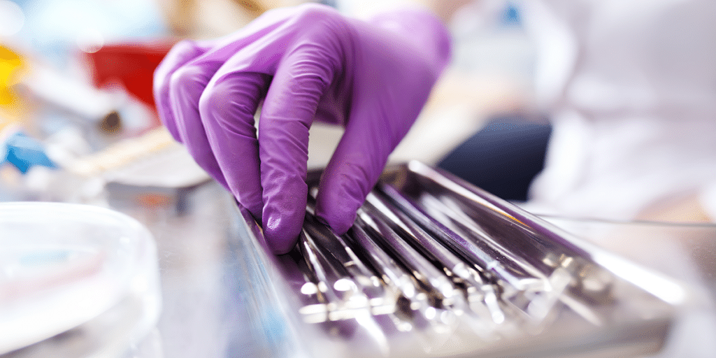 Hand with purple latex glove searching through medical files.