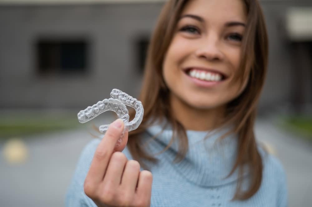 woman holding clear aligners in her hand
