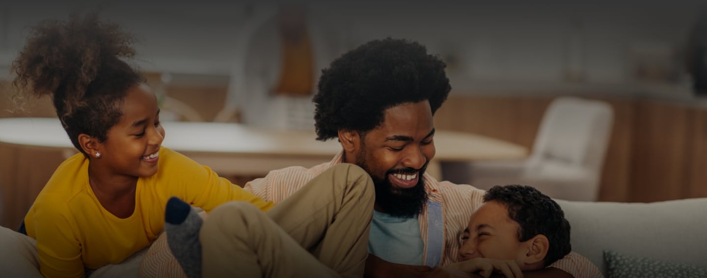 Father plays with sons showing healthy teeth from dental services at Health Centered Dentistry