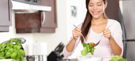 Woman smiling and eating a healthy salad.