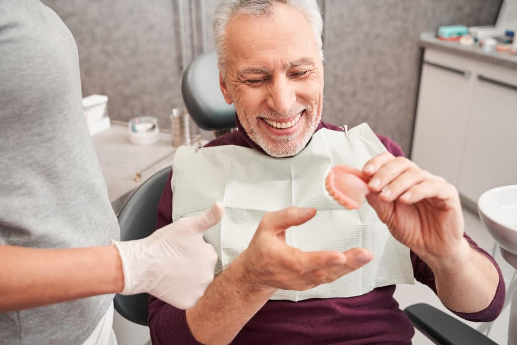 man at the dentist holding his denture