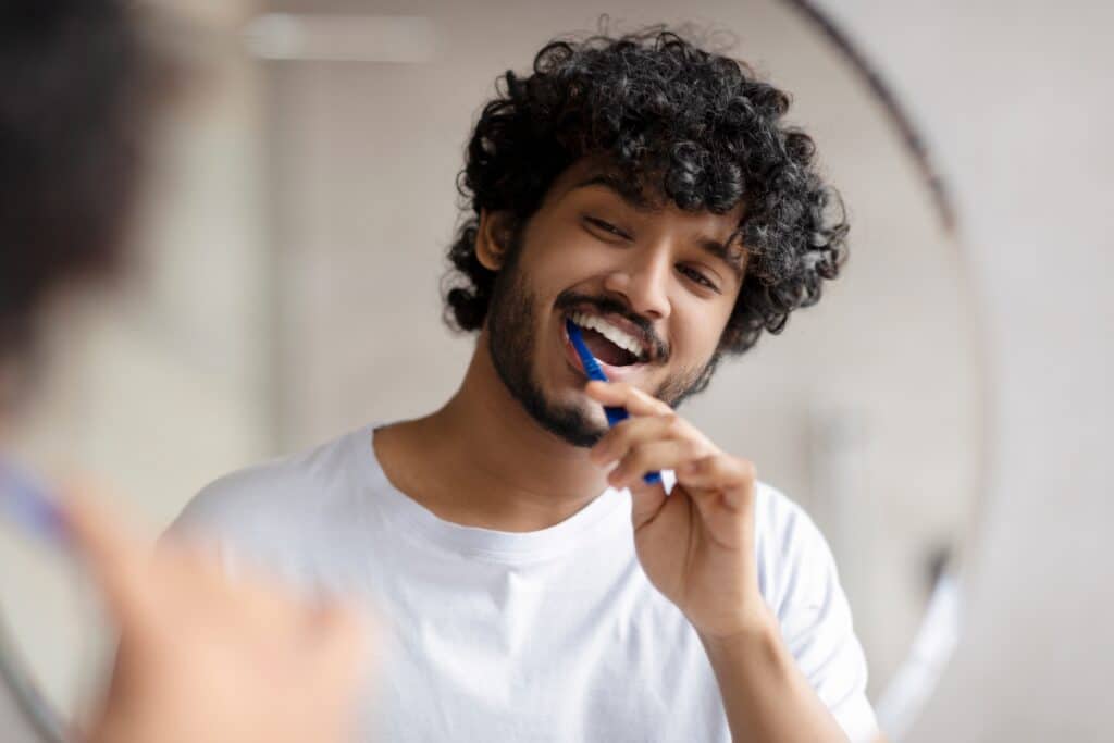 Man looking in a mirror brushing his teeth.