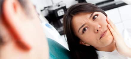 Woman holding face in pain from swollen gums