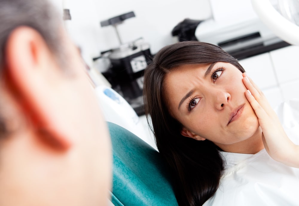 Woman holding face in pain from swollen gums